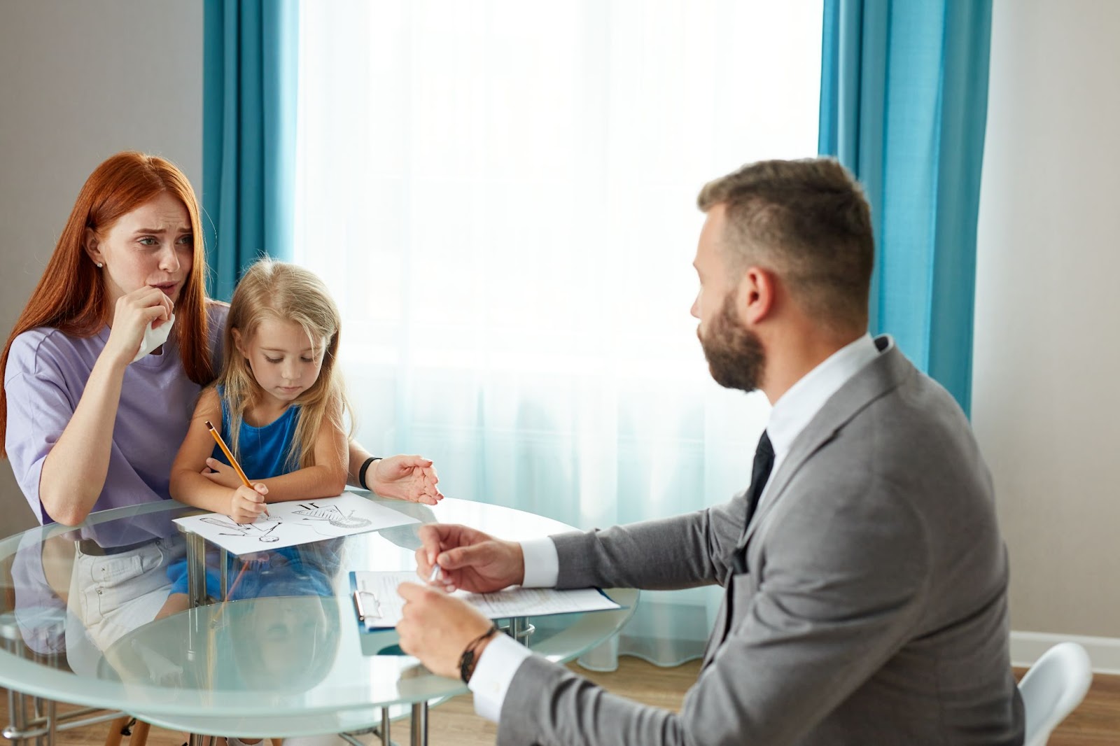 A man, woman, and child seated at a table, possibly discussing family matters with family attorneys or child support services.